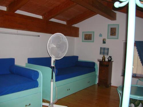 a room with a blue couch and a fan at Villa Silvia in Costa Rei