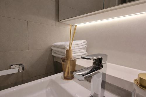 a bathroom with a sink with a light and towels at Stylish Olympic Park Stay - Park View and Dining in Sydney
