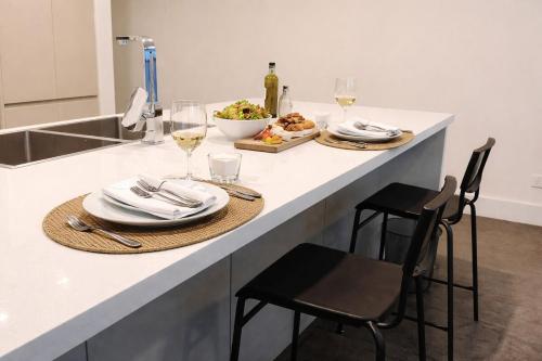 a kitchen counter with a table with plates and glasses of wine at Stylish Olympic Park Stay - Park View and Dining in Sydney