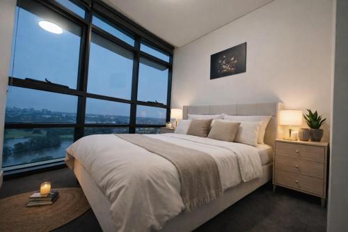 a bedroom with a large bed and large windows at Stylish Olympic Park Stay - Park View and Dining in Sydney
