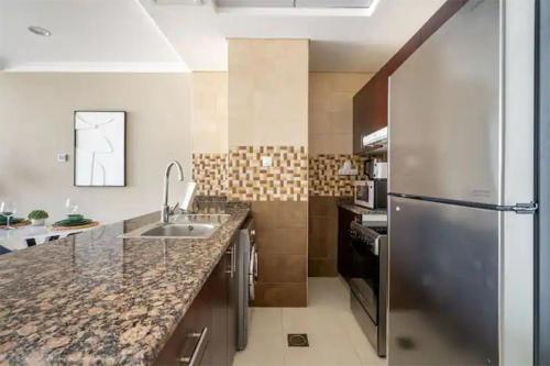 a kitchen with a sink and a refrigerator at Spectacular Studio & 1 Bedroom Apartments in Dubai