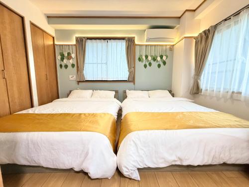 two beds in a room with windows at JR Soubusen Hirai 5mins walk Guest house! 2LDK,Max 8PP! Direct access to Kinshicyo,Akihabara,Shinjyuku! in Tokyo