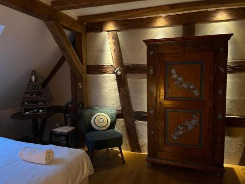 a bedroom with a bed and a chair and a door at Le Saint Michel in Otterswiller