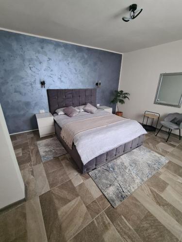 a bedroom with a large bed and a blue wall at Vila Sebas in Zărneşti