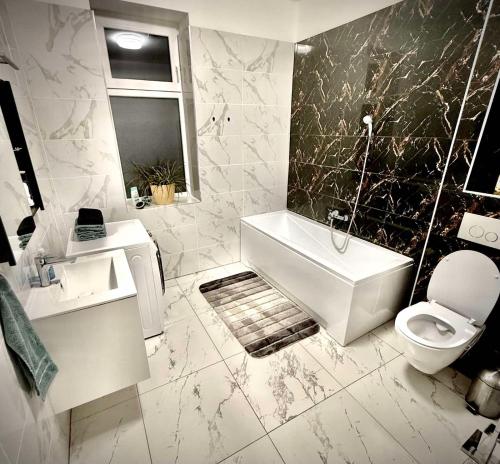 a bathroom with a sink and a tub and a toilet at CFS Apartman in Debrecen