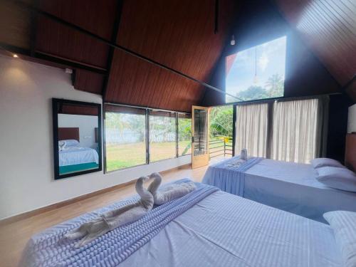 a bedroom with two beds and large windows at Lake Cabana in Udawalawe