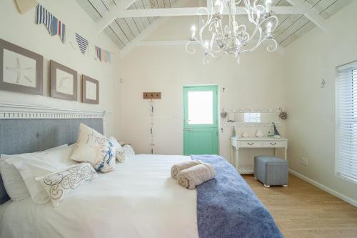 a bedroom with a large white bed with a chandelier at Beach House in Struisbaai