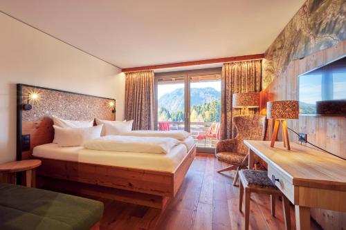 a hotel room with a bed and a desk and a window at Hotel Oberstdorf in Oberstdorf