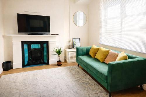 a living room with a green couch and a fireplace at Evo Green Gravesend 2 bed Apartment, 2 mins Station, Town Centre in Gravesend