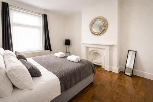 a white bedroom with a bed and a fireplace at Evo Green Gravesend 2 bed Apartment, 2 mins Station, Town Centre in Gravesend