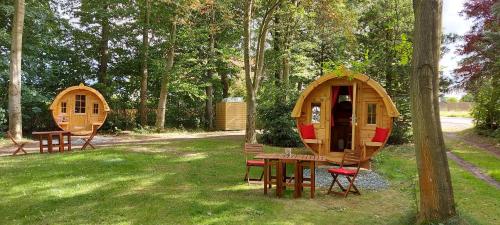 two wooden lodges in a park with a table and chairs at Schlaffass in Neumark