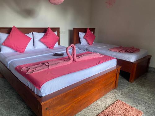 two beds in a room with pink pillows at Happiness Cottage in Ella
