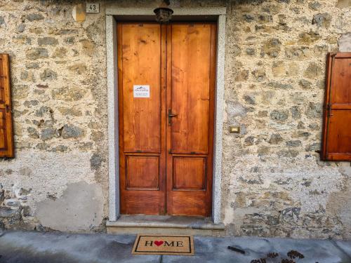 a wooden door on a stone building with a sign in front at Ciasa Cadorina - Relax nelle Dolomiti in Pelos