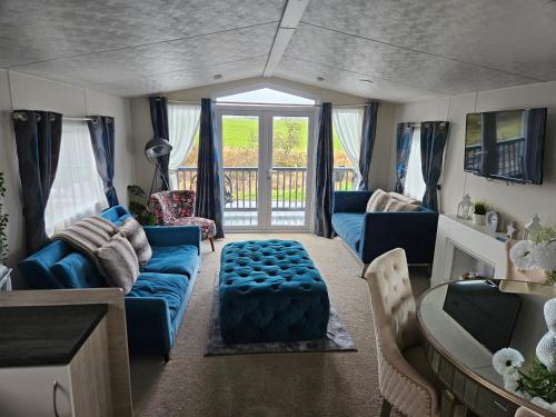 a living room with a blue couch and a table at Foxwood Lodge Private Hot Tub Getaway in Swarland
