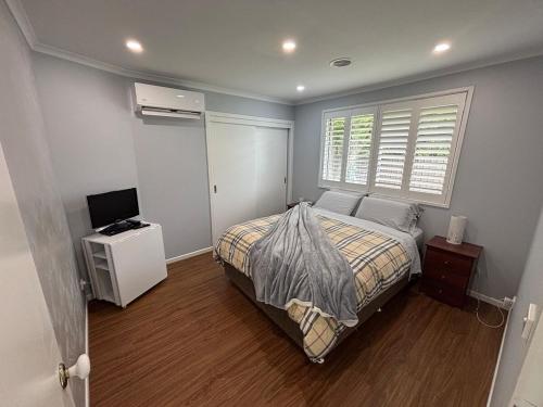 a bedroom with a bed and a television and a window at Guest ensuite room with private entrance in Melbourne
