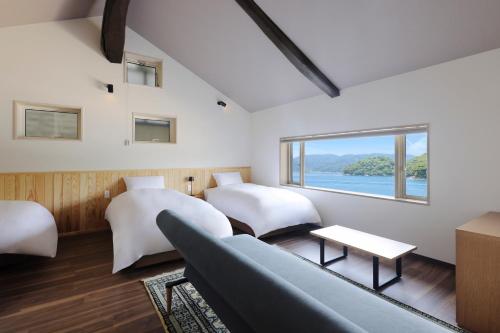 a bedroom with two beds and a couch and a window at 舟屋の宿鍵屋 別館おふくわけ in Kameshima