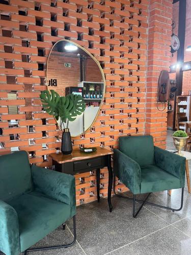 zwei grüne Stühle und ein Tisch mit einem Spiegel in der Unterkunft Hotel Blumenpark in Rio Negro