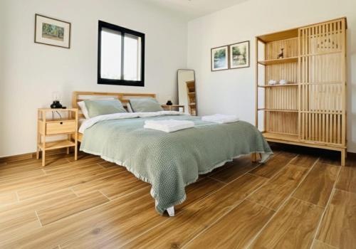 a bedroom with a bed and a wooden floor at The Peleg Tal Unit - היחידה בפלג טל in Dafna