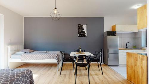 a bedroom with a bed and a table and a kitchen at Apartament Fibra Flat White in Rybnik