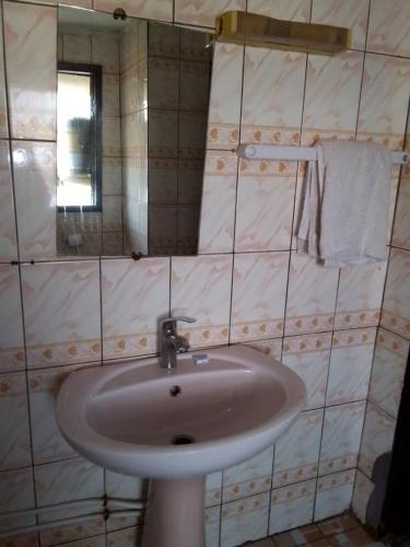 un bagno con un lavandino bianco e uno specchio di NGUELA HoTEL a Yaoundé