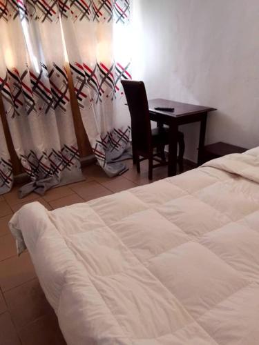 una camera da letto con un letto, una scrivania e un tavolo di NGUELA HoTEL a Yaoundé