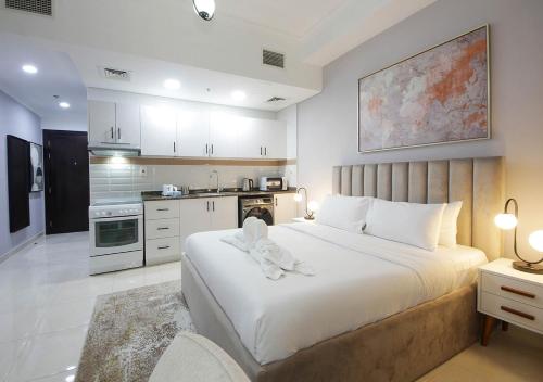 a bedroom with a large white bed and a kitchen at Spectacular Studio & 1 Bedroom Apartments in Dubai