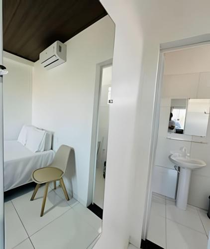 a room with a bed and a chair and a sink at Apartamentos Vitória – Conforto e Excelente Localização in Barreirinhas