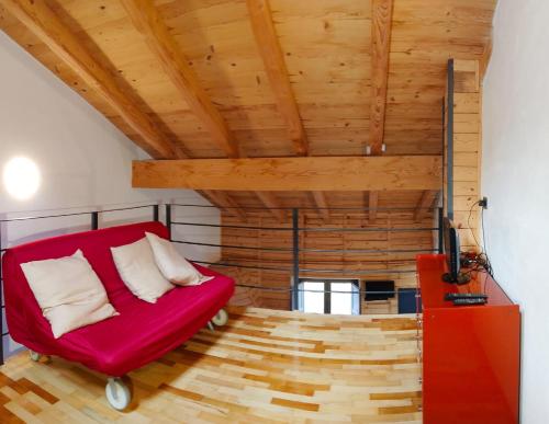 a red couch in a room with a wooden ceiling at Ca Poschiavini - Casa Lares in Casa Piali