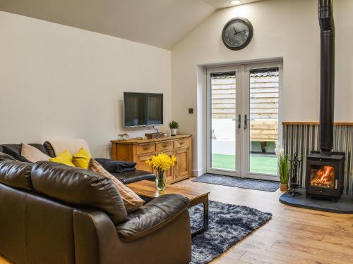 a living room with a leather couch and a fireplace at Perthi Bach in Porthmadog