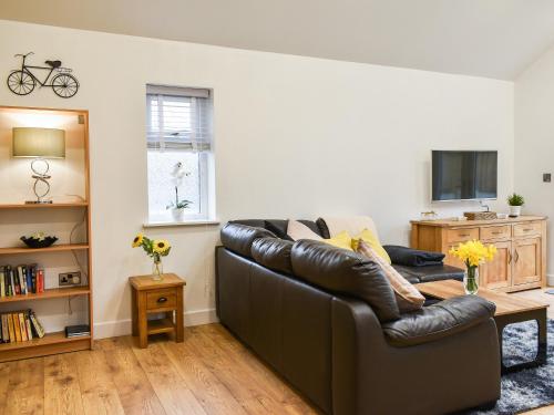 a living room with a leather couch and a tv at Perthi Bach in Porthmadog