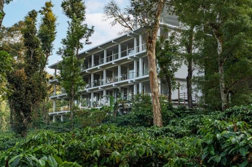 an apartment building in the middle of trees at Itsy Hotels Jammabane Cottage, 5 Minutes To Mountain View Coffee Plantation in Madikeri
