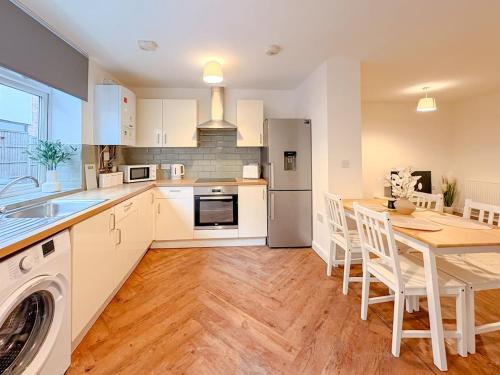 a kitchen with white cabinets and a table with chairs at 58c Thorpe Road - City Centre in Norwich