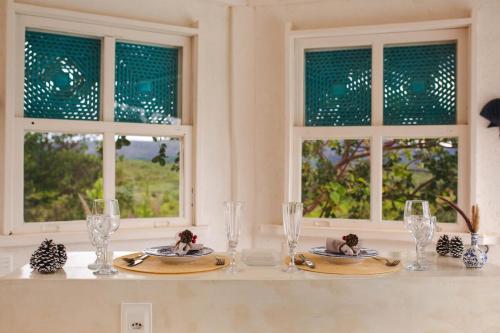 a table with two plates and glasses and two windows at Cipó Cabanas in Santana do Riacho
