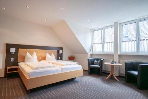 a hotel room with a bed and two chairs at Hotel Moselterrasse in Ediger-Eller