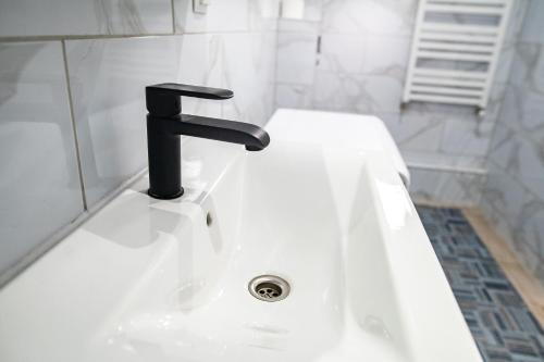 a white sink with a black faucet in a bathroom at Domek Ranczo in Mochnaczka Wyżna
