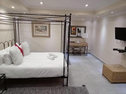 a bedroom with a bed and a desk and a television at Orchids Lodge in Fourways