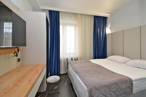 a bedroom with a large bed and blue curtains at Апарт-отель ЛЕВЕЛ Ереван, Ханджян 47 in Yerevan