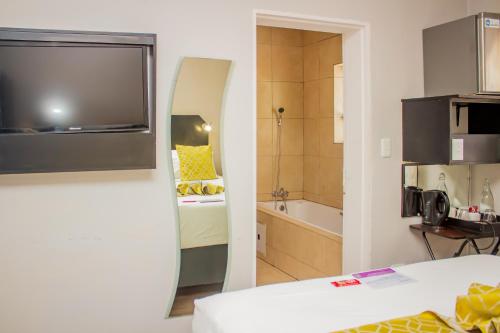 a room with a bed and a bathroom with a tub at Scenery Maqalika Guesthouse in Maseru
