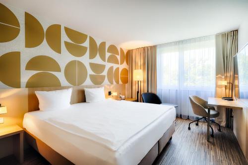 a hotel room with a large bed and a desk at Welcome Hotel Paderborn in Paderborn