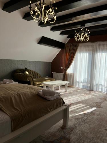 a bedroom with a bed and a couch and chandelier at Poarta Raiului in Tău Bistra
