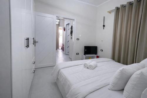 a white bedroom with two beds and a television at Younis chalet in Dahab