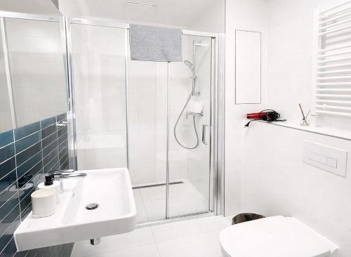 a white bathroom with a shower and a sink at Bella Apartments Brno in Brno