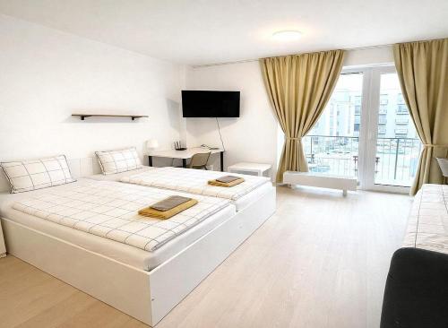 a white bedroom with a large bed and a television at Bella Apartments Brno in Brno