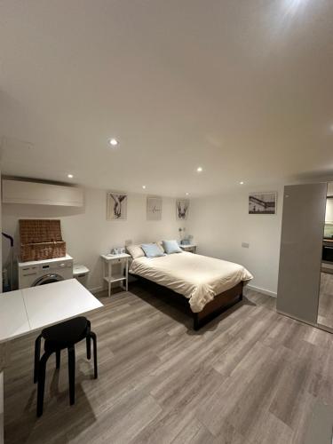 a bedroom with a bed and a table and a desk at Cosy, self-contained guest house in Thornton Heath