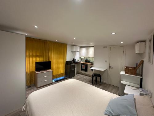 a bedroom with a white bed and a kitchen at Cosy, self-contained guest house in Thornton Heath