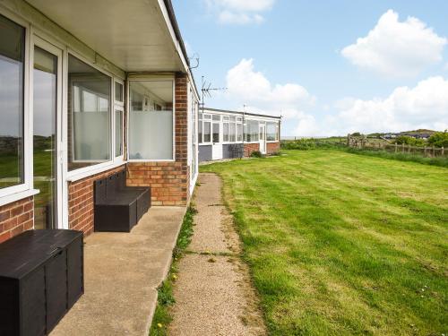 a brick building with windows and a grass field at Eastcliff Bungalow in Mundesley