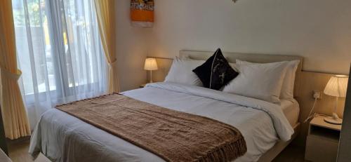 a bedroom with a bed with white sheets and pillows at Cozy 1Bedroom House with Kitchen Work Space in Nusa Dua