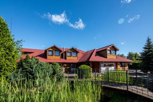 a house with a bridge over a river at Karczma Pod Topolami in Ratowo Piotrowo