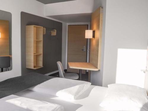 a bedroom with a bed and a desk and a mirror at B&B Hotel Böblingen in Böblingen