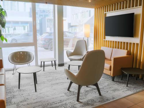 a living room with a couch and chairs and a tv at B&B Hotel Böblingen in Böblingen